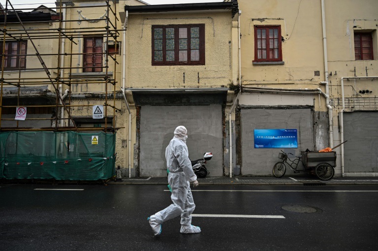 موظف يرتدي اللباس الواقي يسير قرب حي فرض فيه إغلاق بسبب تجدد انتشار الوباء في شنغهاي في 17 آذار/مارس 2022(ا ف ب)