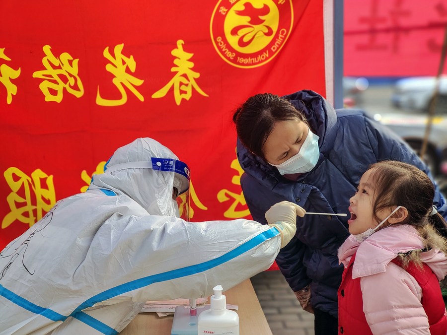 في الصورة الملتقطة يوم 11 يناير 2022، عامل طبي يأخذ عينة مسحة الحلق من طفلة في موقع لاختبار الحمض النووي للكشف عن كوفيد-19 في مدينة آنيانغ بمقاطعة خنان في وسط الصين. (شينخوا)