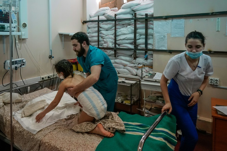 ممرضان يساعدان فتاة مصابة أُجليت من مدينة ماريوبول في مستشفى للأطفال في زابوريشزيا في 22 آذار/مارس 2022 (ا ف ب)