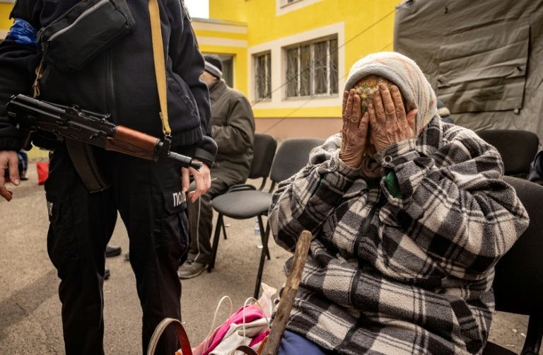 امرأة مرافقة من قبل الشرطة بعد فرارها من منزلها في ضواحي كييف في 26 آذار/مارس 2022 (ا ف ب)