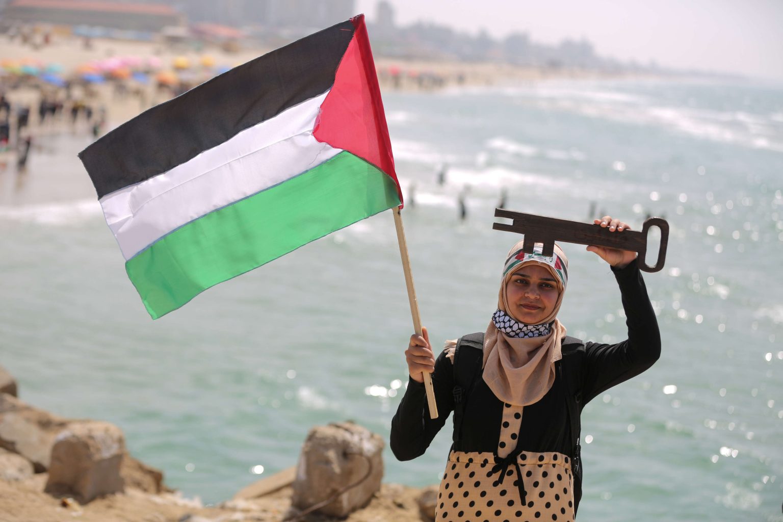 فلسطينية تحمل علم بلادها ورمز مفتاح العودة (الأناضول)