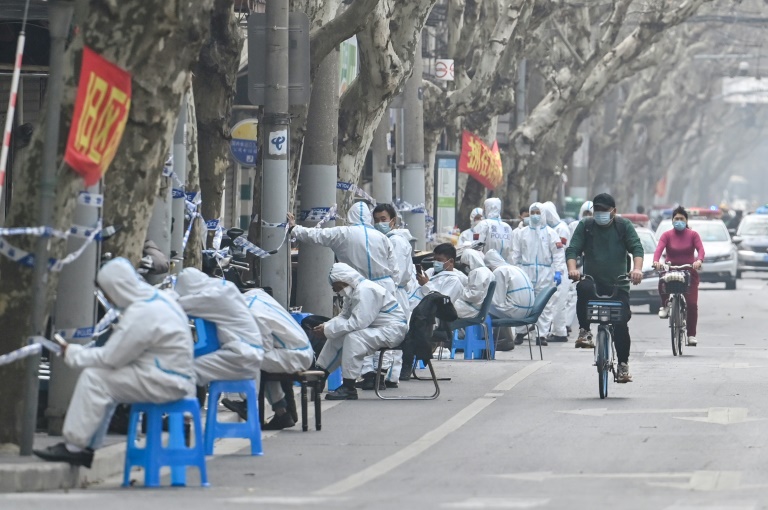  موظفون ببزات واقية قرب مناطق مغلقة بعد اكتشاف إصابات جديدة بكوفيد في شنغهاي بتاريخ 14 آذار/مارس 2022 (ا ف ب)