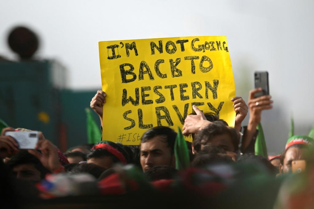أحد مؤيدي حزب تحريك إنصاف الباكستاني الحاكم يحمل لافتة خلال مسيرة لرئيس الوزراء الباكستاني عمران خان في إسلام أباد في 27 مارس (أ ف ب)