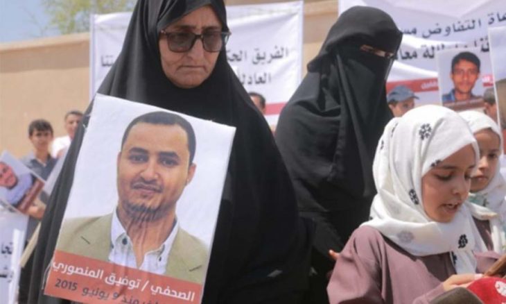 والدة الصحافي اليمني توفيق المنصور المعتقل في سجون الحوثي تحمل صورته (التواصل الاجتماعي)