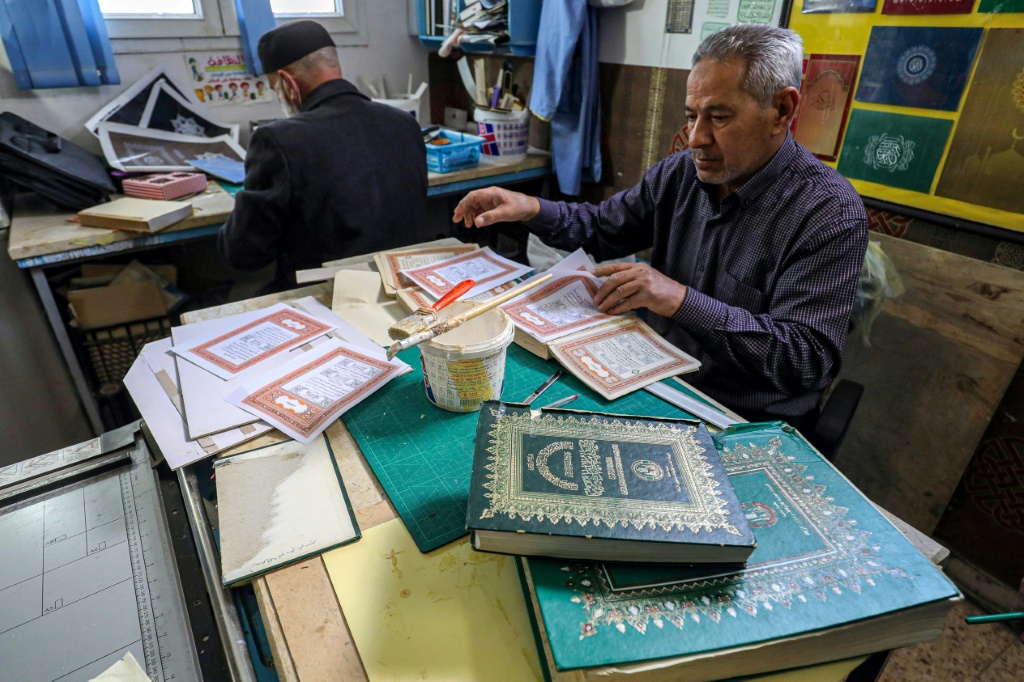    رجل يعمل على تأهيل مصحف قديم في إحدى الورش المخصصة للترميم في ليبيا (أ ف ب)