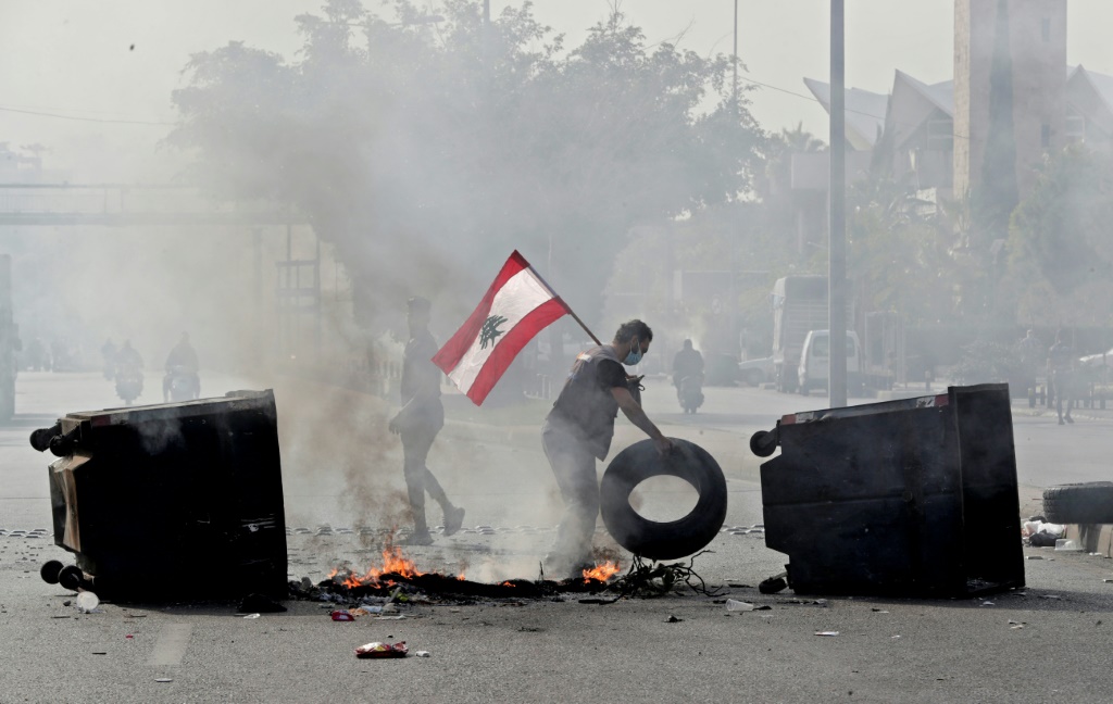 شاب لبناني يشارك في قطع طريق رئيسي في بيروت خلال تظاهرة احتجاجية في 29 تشرين الثاني/نوفمبر 2021 على وقع الأزمة الاقتصادية غير المسبوقة التي تعصف بلبنان منذ أكثر من عامين (أ ف ب)