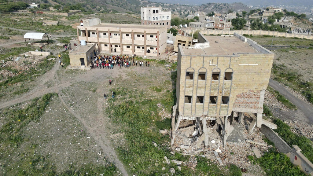 لقطة من الجو تظهر طلابا أثناء حضورهم درسا في مجمع مدرستهم المدمّر في تعز بتاريخ 30 آب/اغسطس 2021 (أ ف ب)