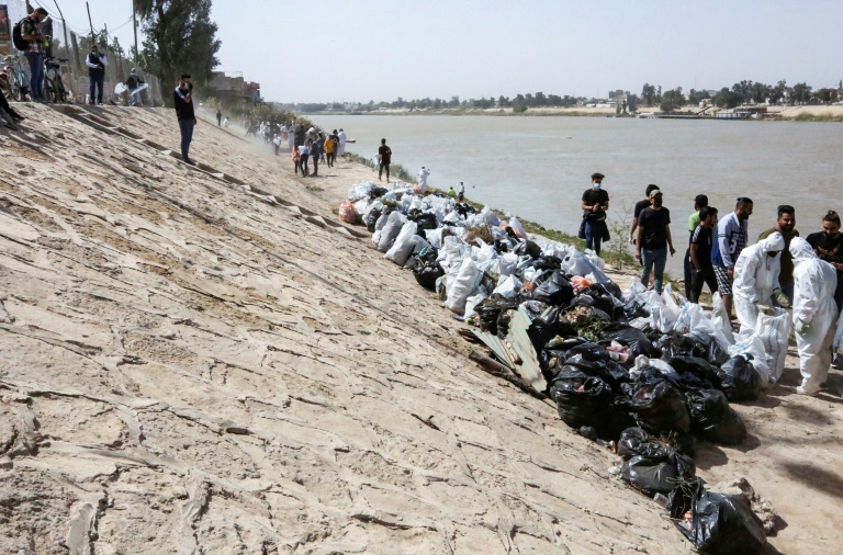   متطوعون شباب يشاركون في حملة تنظيف على ضفاف نهر دجلة في بغداد في 11 اذار/مارس 2022 (ا ف ب)