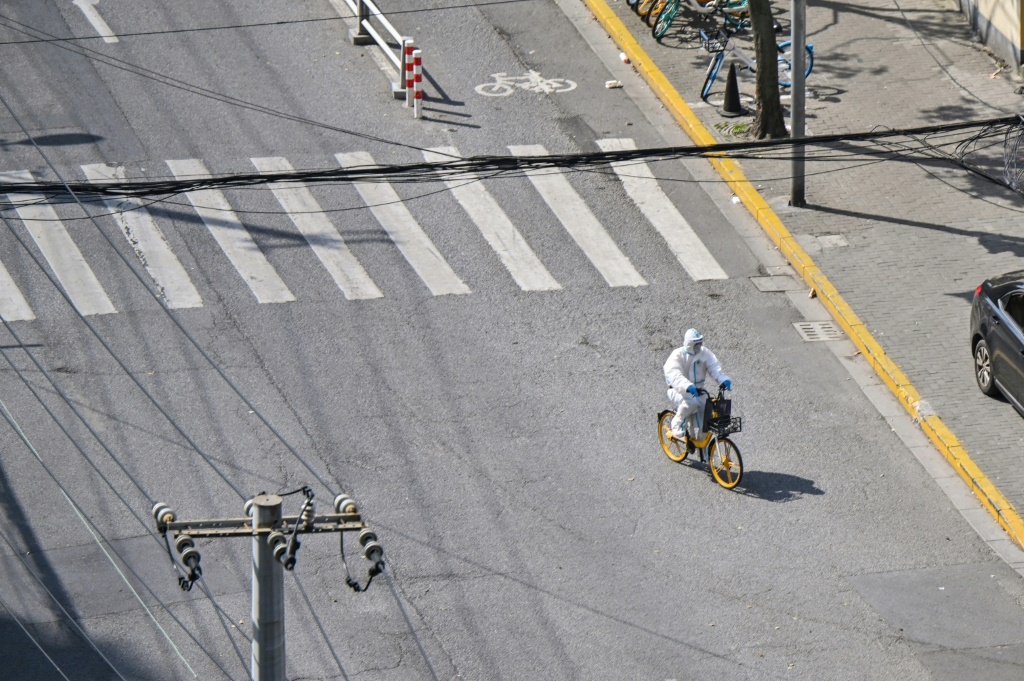 عامل صحة بملابس واقية يعبر شارعا في شنغهاي على دراجة خلال تدابير إغلاق في 8 نيسان/أبريل 2022 (ا ف ب)