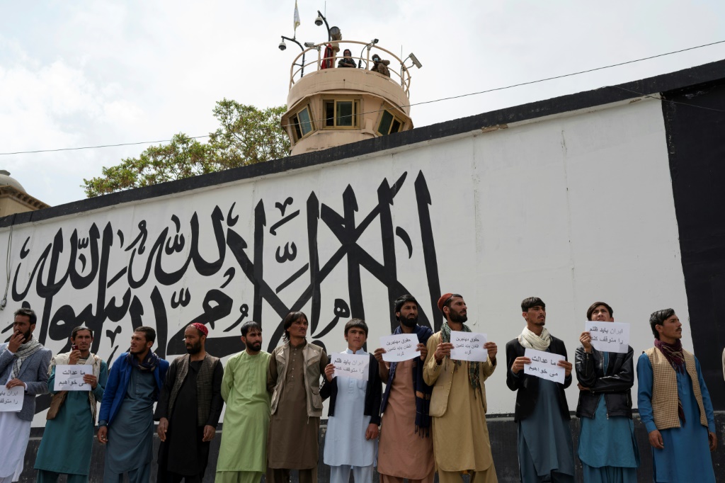 متظاهرون يحملون لافتات خلال احتجاج قرب ساحة أحمد شاه مسعود في كابول في 12 نيسان/أبريل 2022 بعد انتشار مقاطع فيديو يُزعم أنها تُظهر لاجئين أفغان يتعرضون للضرب على أيدي إيرانيين(ا ف ب)
