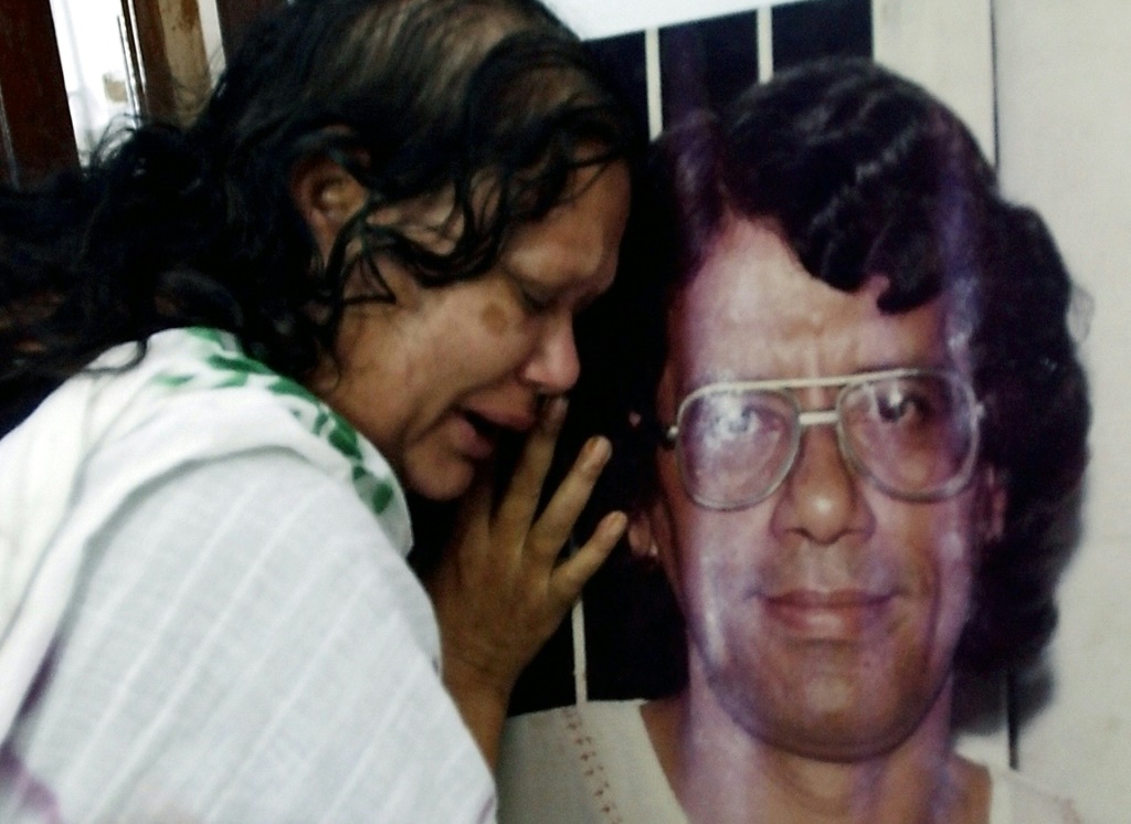 قريب للكاتب البنغلاديشي همايون آزاد يبكي بجانب صورته بعد هجوم عام 2004 الذي أودى بحياته (ا ف ب)