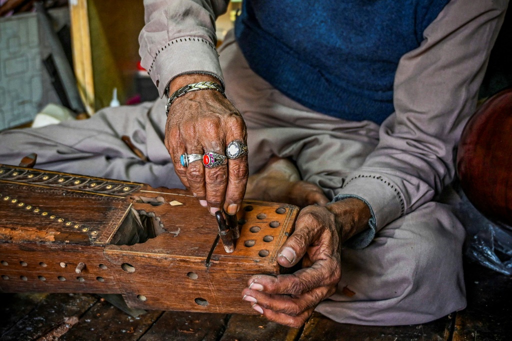 أستاذ ضياء الدين يصلح آلة سارانغي تقليدية في متجره بمدينة لاهور الباكستانية في 24 شباط/فبراير 2022 (ا ف ب)