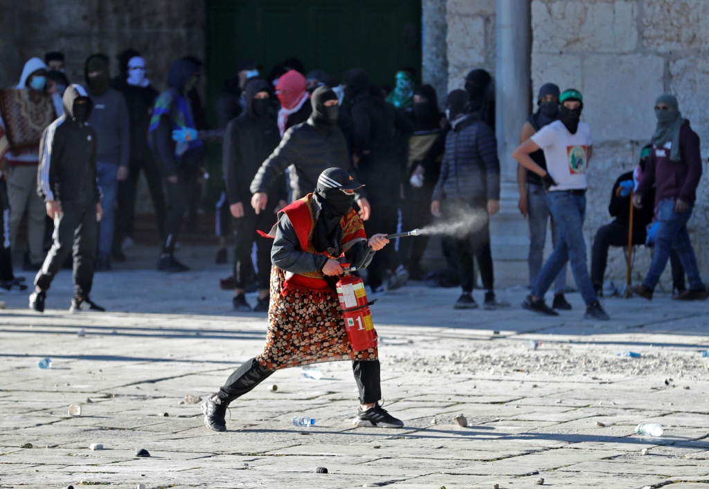 فلسطيني يستخدم مطفأة حريق خلال اشتباكات مع القوات الإسرائيلية في باحة المسجد الأقصى في 15 نيسان/أبريل 2022(ا ف ب)