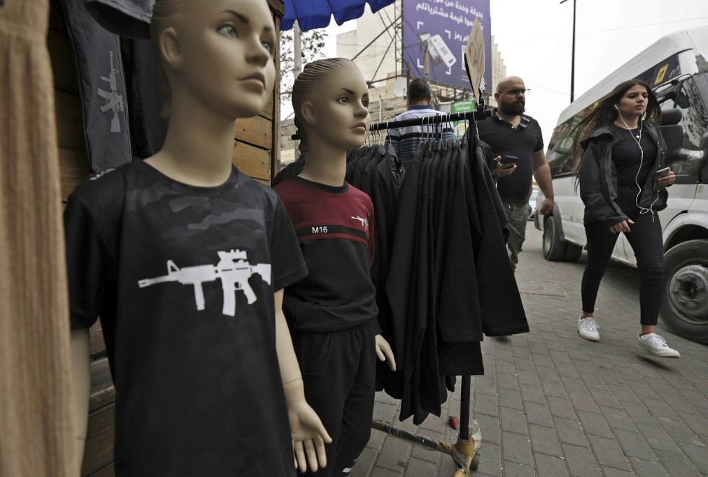  قمصان قطنية تحمل صورة رشاش "أم 16" معروضة في سوق في رام الله في 20 نيسان/أبريل 2022 (ا ف ب)