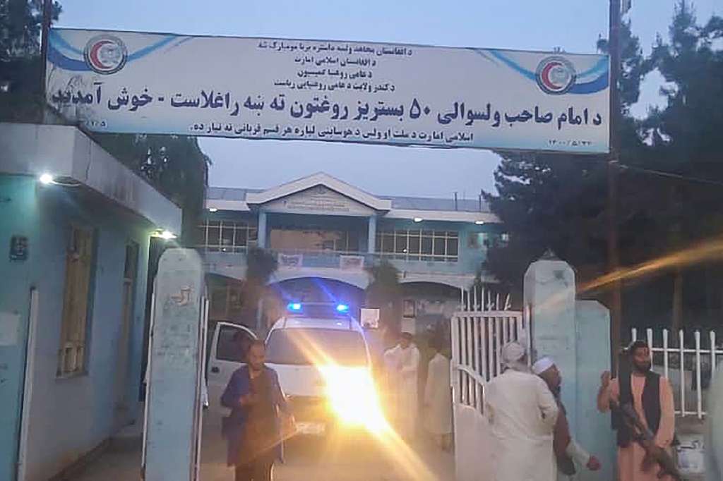    مقاتلو طالبان وطاقم طبي يقف خارج بوابة المستشفى بعد انفجار في حي الإمام صاحب شمال مدينة قندوز (أ ف ب)