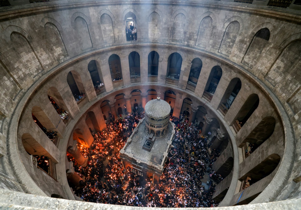 المسيحيون الأرثوذكس يجتمعون مع الشموع المضاءة حول Edicule ، الذي يُعتقد تقليديًا أنه موقع دفن يسوع المسيح ، خلال احتفال النار المقدسة في كنيسة القيامة بالقدس (أ ف ب)