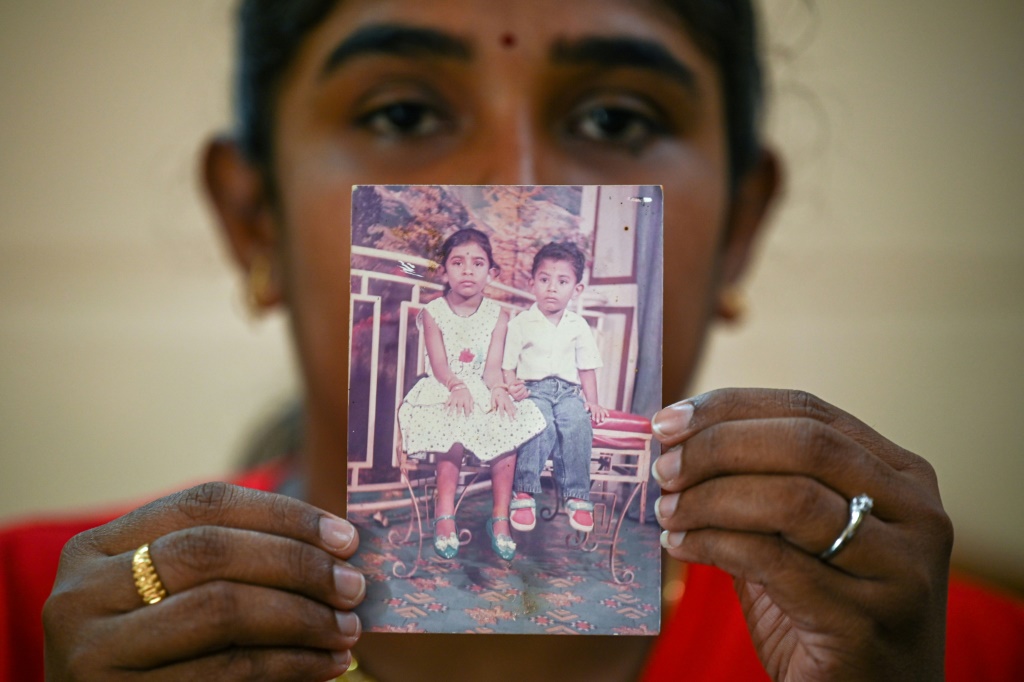 سرميلا شقيقة ناغاينثران ك. دارمالينغام تحمل صورة تظهرهما خلال الطفولة، خلال مقابلة مع وكالة فرانس برس في منزل العائلة في ماليزيا في 14 تشرين الثاني/نوفمبر 2021 (ا ف ب)