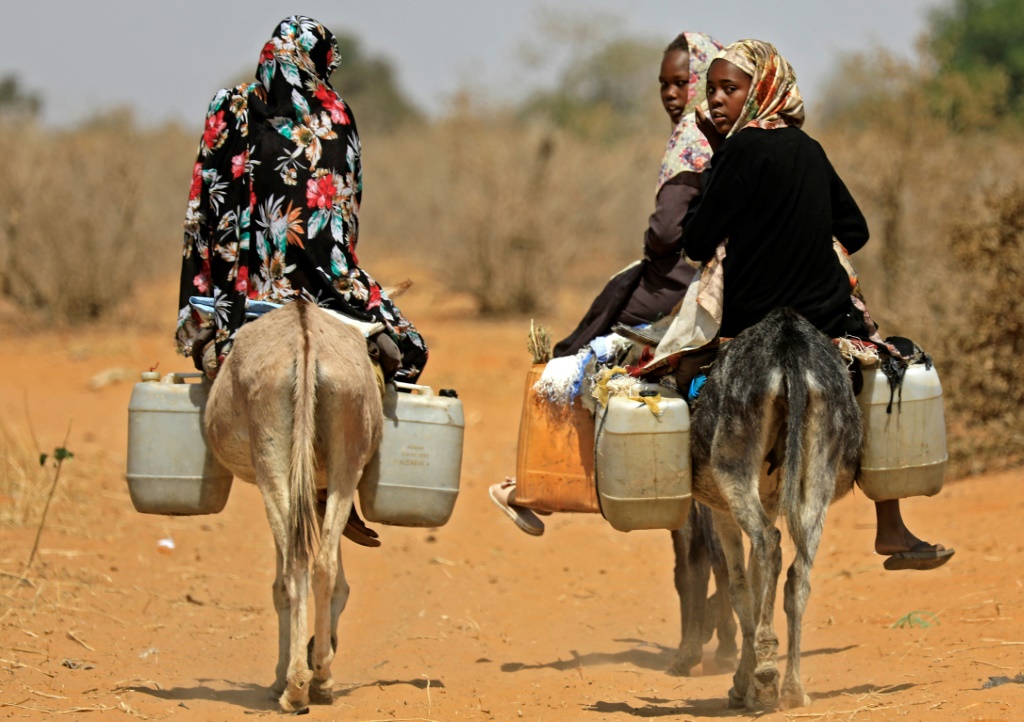 نساء سودانيات ينقلن المياه في جنوب دارفور ، كما يظهر في هذه الصورة في فبراير 2021 ؛ واندلعت أعمال عنف مميتة بسبب النزاعات على الأراضي والماشية والوصول إلى المياه والمراعي (أ ف ب)