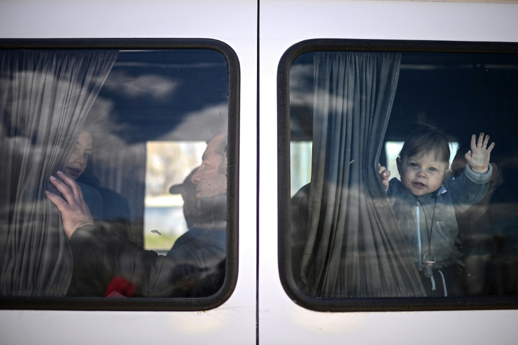 وداعا للمنزل: طفل لاجئ أوكراني يلوح من حافلة صغيرة تقله هو ووالدته إلى مولدوفا (أ ف ب)