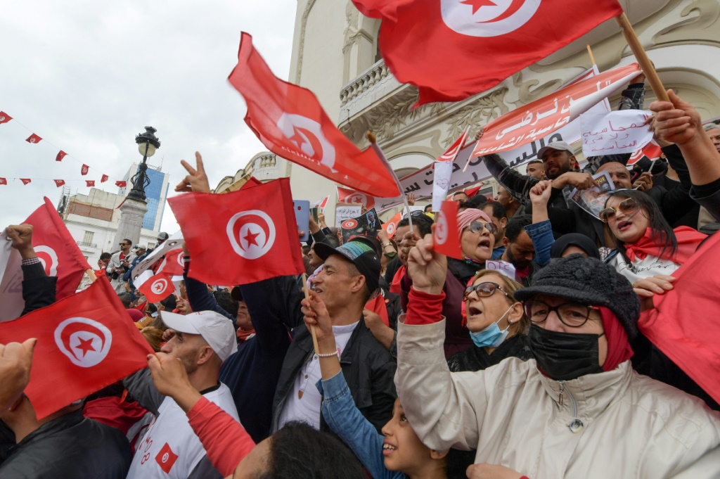    متظاهرون تونسيون يرددون هتافات ويلوحون بعلم بلادهم دعما للرئيس قيس سعيد في العاصمة تونس (أ ف ب)
