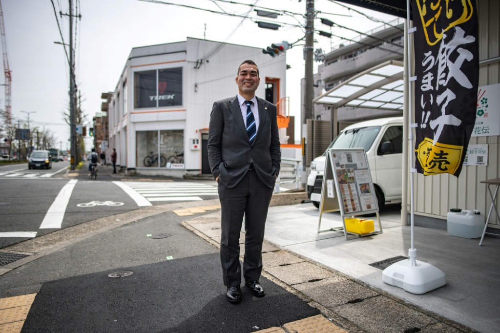صورة التقطت في 11 نيسان/أبريل 2022 لمصارع السومو المعتزل تاكويا سايتو أمام مصنع للمأكولات المجمدة يديره صديقه توموهيكو ياماغوتشي في كيوتو (اف ب).