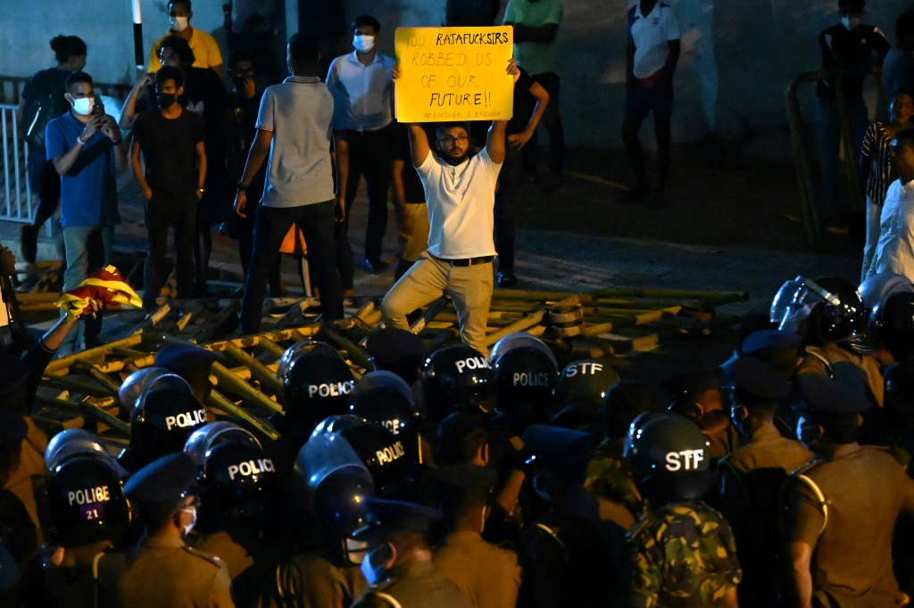 متظاهر يرفع لافتة أمام عناصر الشرطة خلال احتجاج على ارتفاع الأسعار ونقص الوقود، عند طريق مؤد إلى مقر رئيس الحكومة في كولومبو، في 7 نيسان/أبريل 2022 (ا ف ب)