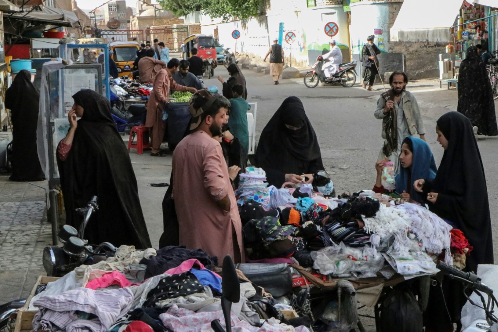 نساء يشترين الملابس من كشك في الشارع في هرات (ا ف ب)