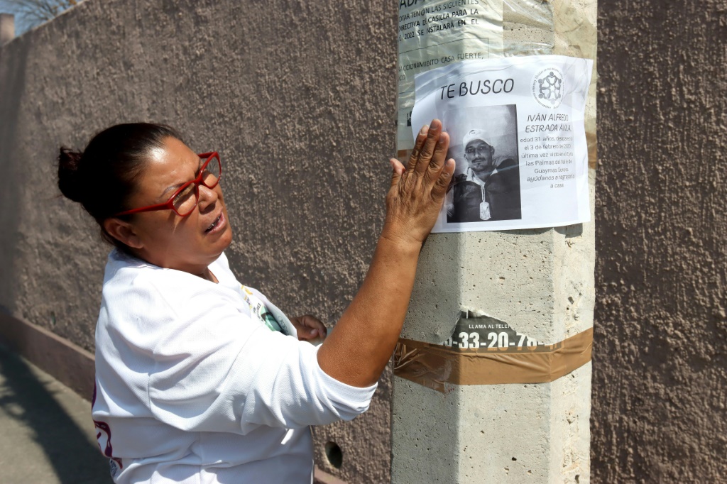أزوليما إسترادا تعلّق لافتة عليها صورة ابنها المفقود في ولاية خاليسكو المكسيكية (ا ف ب)