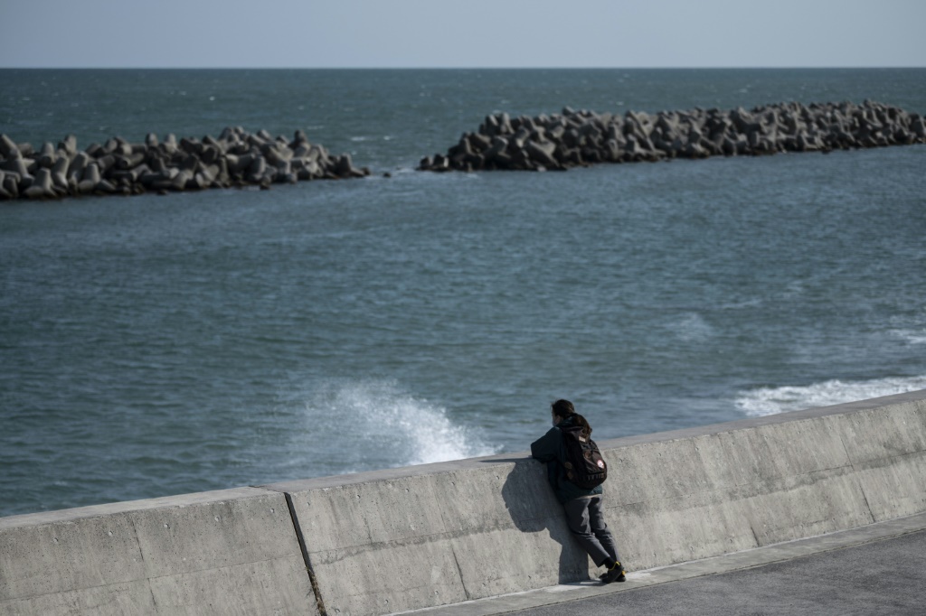    امرأة تقف عند سد قبالة البحر في هيسانوهاما بمقاطعة فوكوشيما اليابانية في الذكرى السنوية العاشرة للكارثة النووية التي وقعت في المنطقة في 11 آذار/مارس 2011 (أ ف ب)