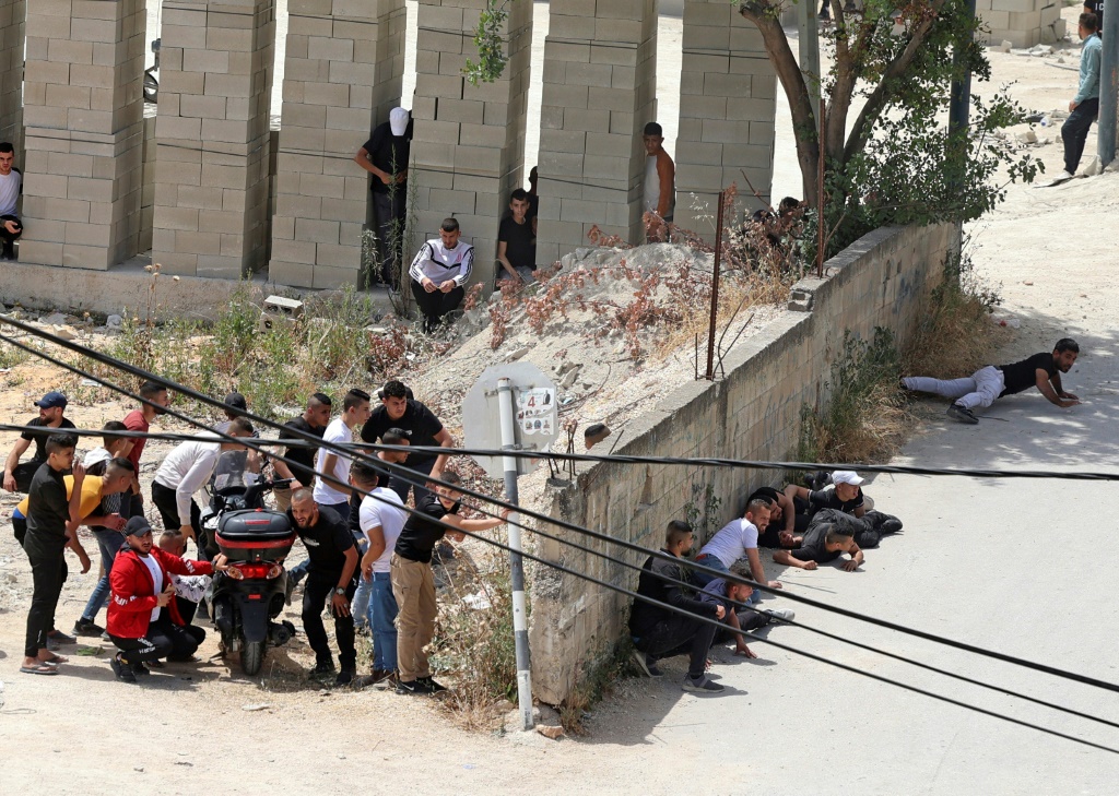 فلسطينيون يحتمون خلال اشتباكات مع قوات الجيش الإسرائيلي في مدينة جنين بالضفة الغربية في 13 أيار/مايو، 2022 (أ ف ب)