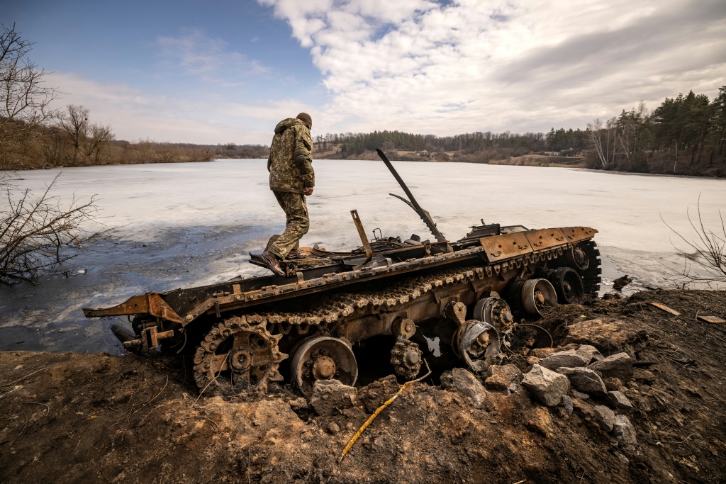 جندي أوكراني يقف بالقرب من دبابة روسية مدمرة في شمال شرق مدينة تروستيانتس ، في 29 مارس 2022 (أ ف ب)