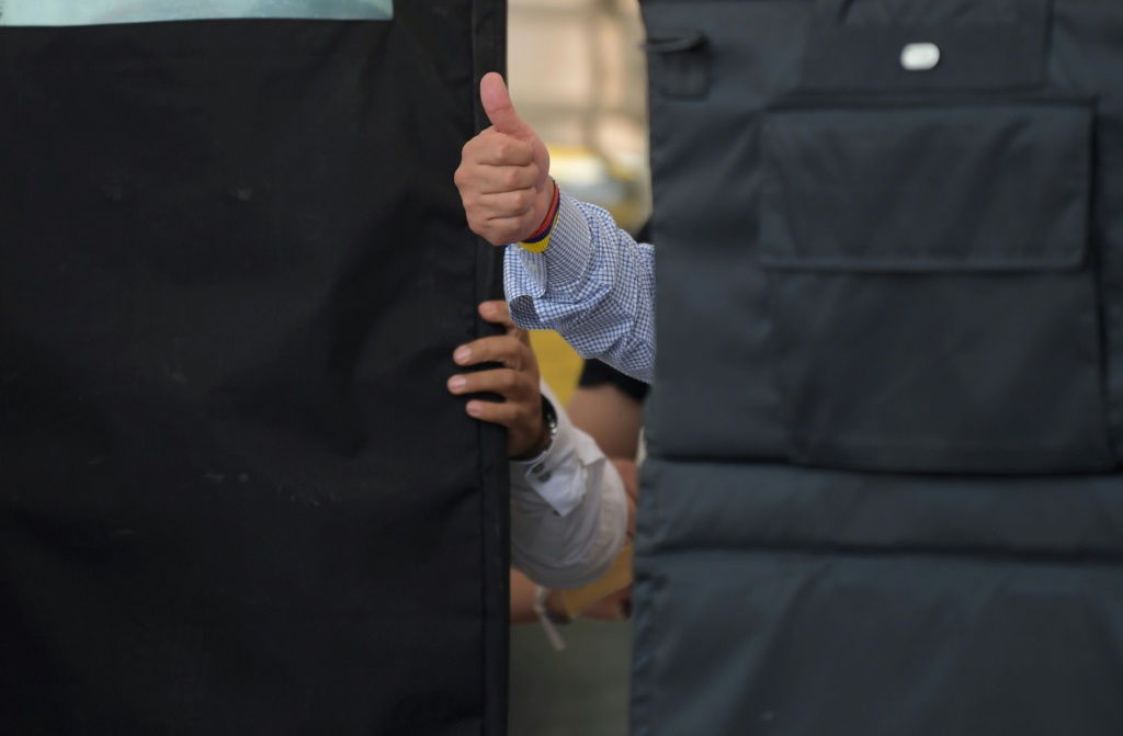 المرشح الرئاسي الكولومبي اليساري غوستافو بيترو يلوح بمؤيديه من خلف دروع واقية من الرصاص خلال مسيرة انتخابية في مايو 2022 (أ ف ب)