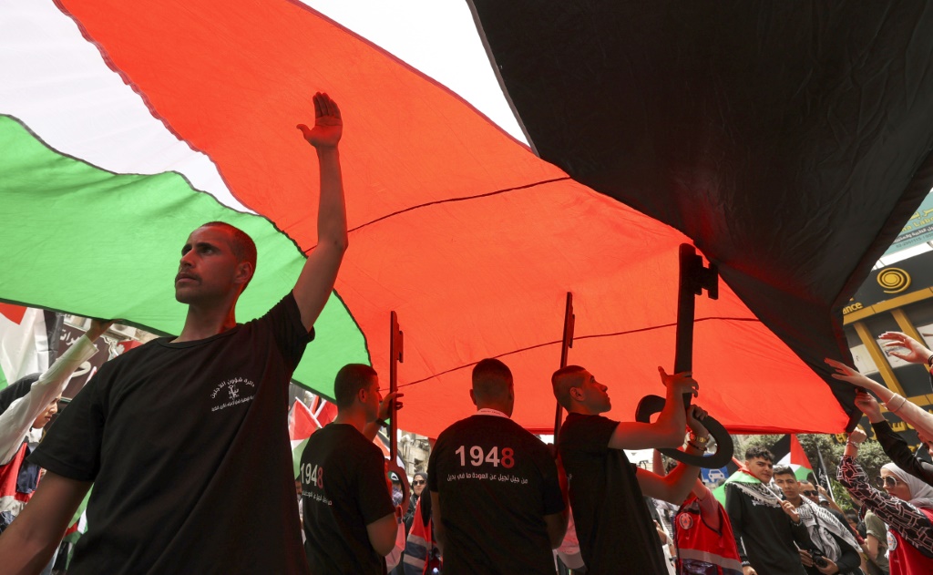 فلسطينيون يرفعون علم وطني ومفتاح عودة كبيرة كرمز للنكبة خلال مسيرة مركزية انطلقت وسط مدينة رام الله في الذكرى 74 للنكبة في 15 أيار/مايو 2022 (أ ف ب)