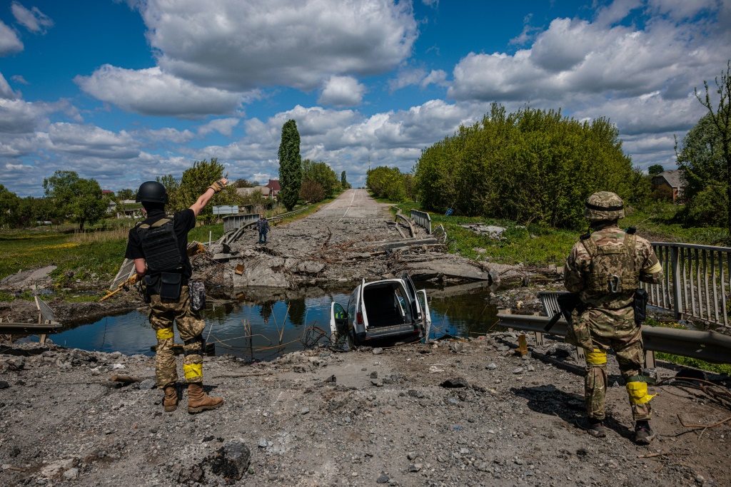 جنود من وحدة القوات الخاصة الأوكرانية في كراكن يتحدثون إلى رجل عند جسر مدمر بالقرب من قرية روسكا لوزوفا ، شمال خاركيف (أ ف ب)