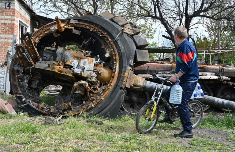 مواطن ينظر إلى دبابة روسية مدمرة قرب منزل في قرية مالا روغان شرق خاركيف، في 15 أيار/مايو 2022 (ا ف ب)