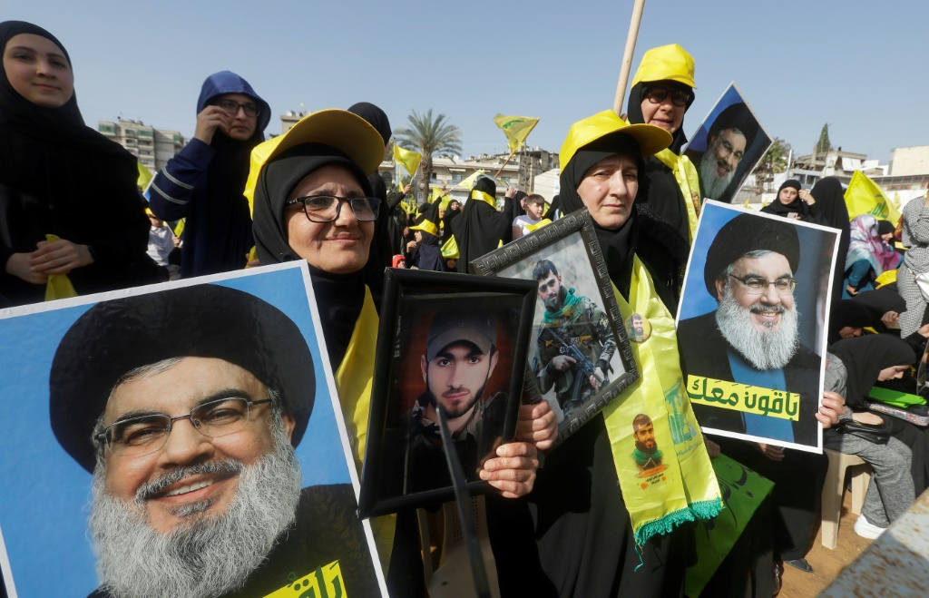    أنصار جماعة حزب الله اللبنانية الشيعية المدعومة من إيران يحملون صوراً لزعيم الجماعة حسن نصر الله (أ ف ب)