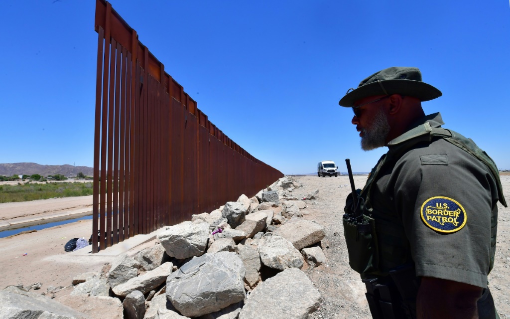 ضابط من حرس الحدود الأمريكي يقف حراسة عند فجوة في الجدار الحدودي الذي يفصل مدينة ألجودونيس ، المكسيك ، عن يوما ، أريزونا ، في 16 مايو 2022 (أ ف ب)