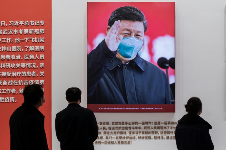 صورة تم التقاطها في 15 كانون الثاني/يناير 2021، ينظر الناس إلى صورة الرئيس الصيني شي جينبنغ خلال معرض حول مكافحة كوفيد19 في ووهان (ا ف ب)
