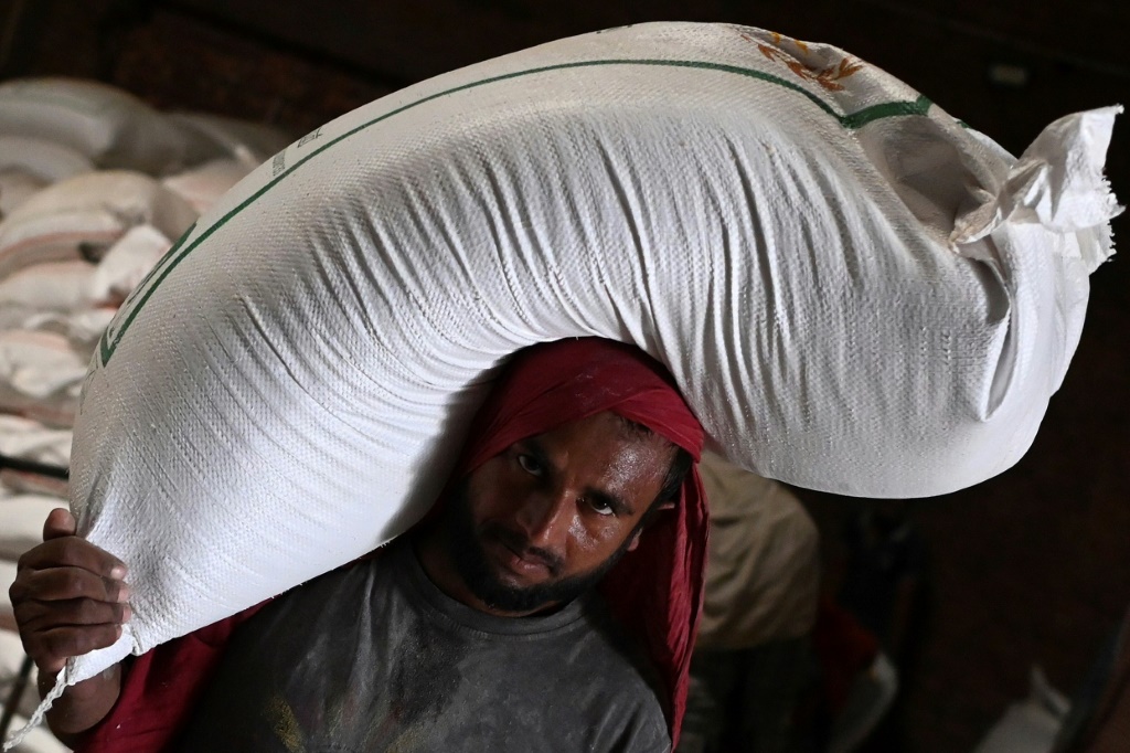 عامل يحمل كيسا من القمح إلى شاحنة في مطحنة في كانا بولاية بنجاب الهندية في 18 أيار/مايو 2022 (ا ف ب)