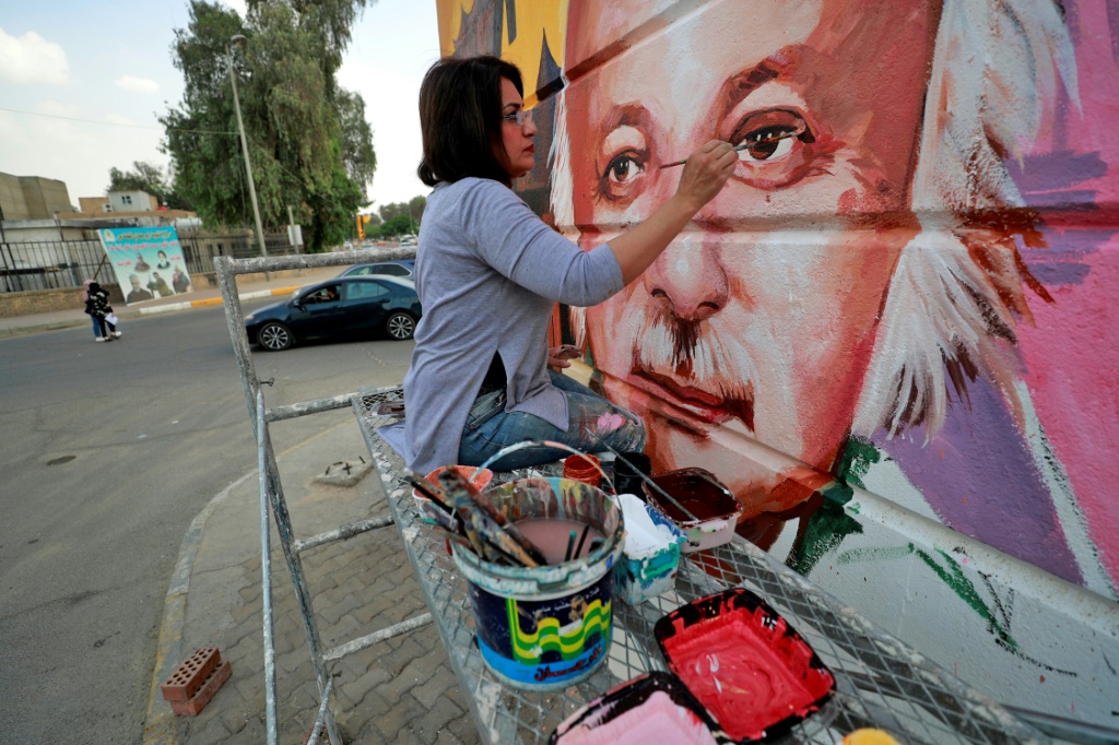 الفنانة العراقية وجدان الماجد تضع بعض اللمسات على جدارية تظهر الشاعر العراقي مظفر النواب في بغداد في 26 نيسان/ابريل 2022 (ا ف ب)