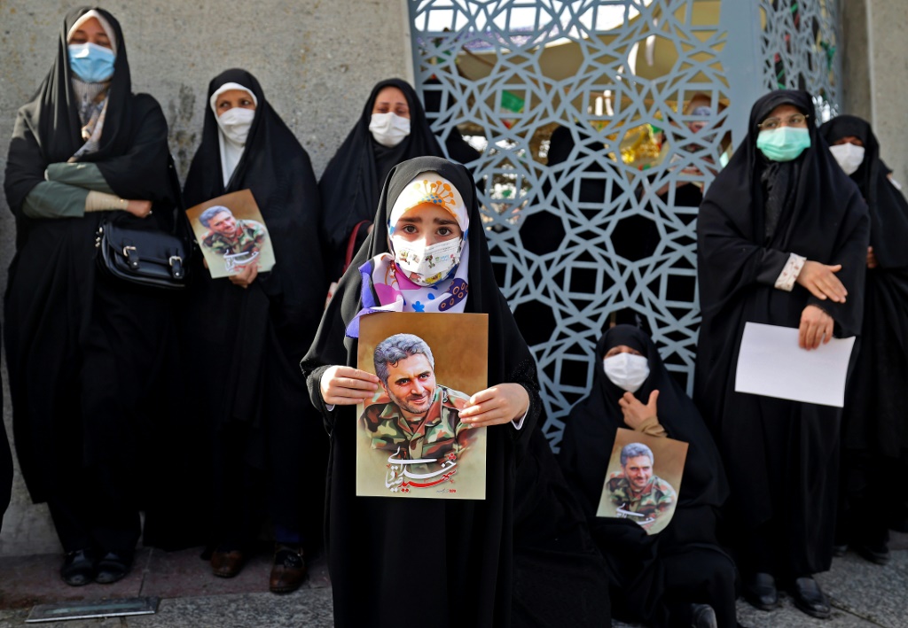 مشيعون يحملون صور "شهداء" آخرين قتلوا خلال العمليات الإيرانية في الخارج وهم ينضمون إلى الحشود الكبيرة في الشوارع لحضور جنازة خدي (أ ف ب)