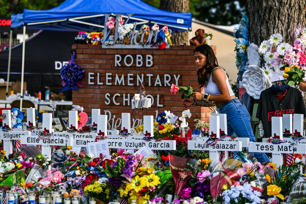 فتاة تضع الزهور في نصب تذكاري مؤقت في مدرسة روب الابتدائية في يوفالدي في تكساس في 28 أيار/مايو 2022 (ا ف ب)