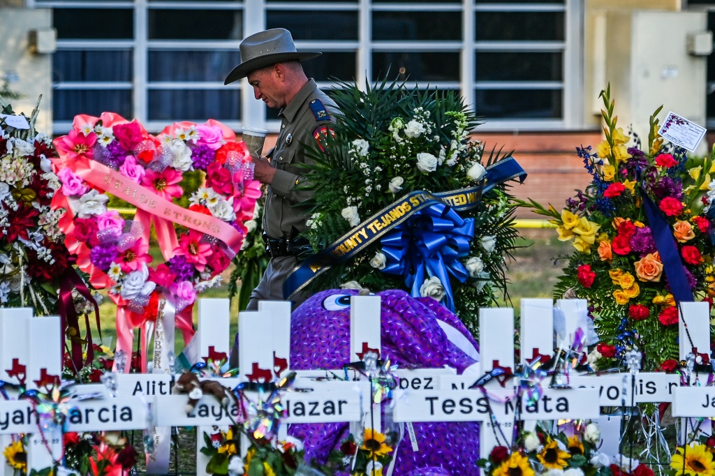 شرطي يقف قرب النصب التذكاري المؤقت لضحايا إطلاق النار خارج مدرسة روب الابتدائية في يوفالدي في تكساس في 28 أيار/مايو 2022 (ا ف ب)
