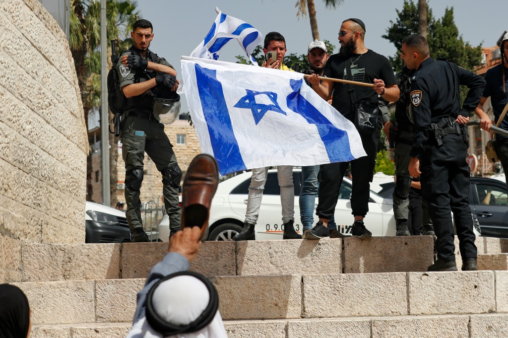 فلسطيني في باب العامود يرفع حذاء في مواجهة إسرائيليين يحملون أعلام بلادهم في 29 أيار/مايو 2022 (ا ف ب)