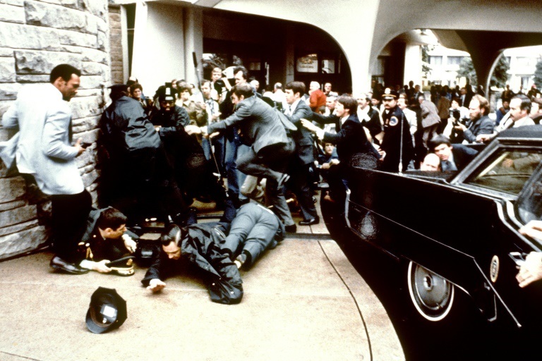 رجال الخدمة السرية يحاولون حماية ريغان بعد إطلاق هينكلي النار عليه أمام فندق في واشنطن (ا ف ب)