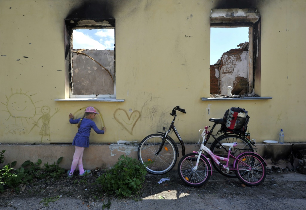 فتاة ترسم على جدار منزل مدمر في أندريفكا في منطقة العاصمة الأوكرانية كييف في 03 حزيران/يونيو 2022 (ا ف ب)