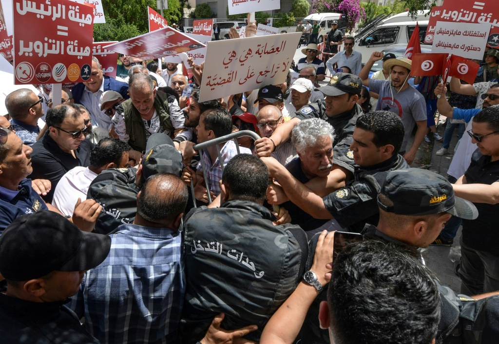 المتحدث باسم حزب العمال التونسي حمّة الهمامي بين متظاهرين منعتهم الشرطة من الاقتراب من مقر الهيئة العليا المستقلة للانتخابات في العاصمة تونس بتاريخ 4 حزيران/يونيو 2022 (أ ف ب)