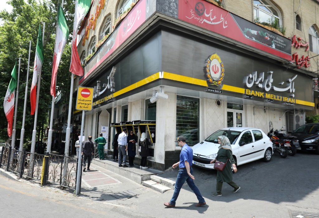 أشخاص يمرون بفرع بنك ملي في العاصمة الإيرانية طهران في 20 مايو 2019 (ا ف ب)