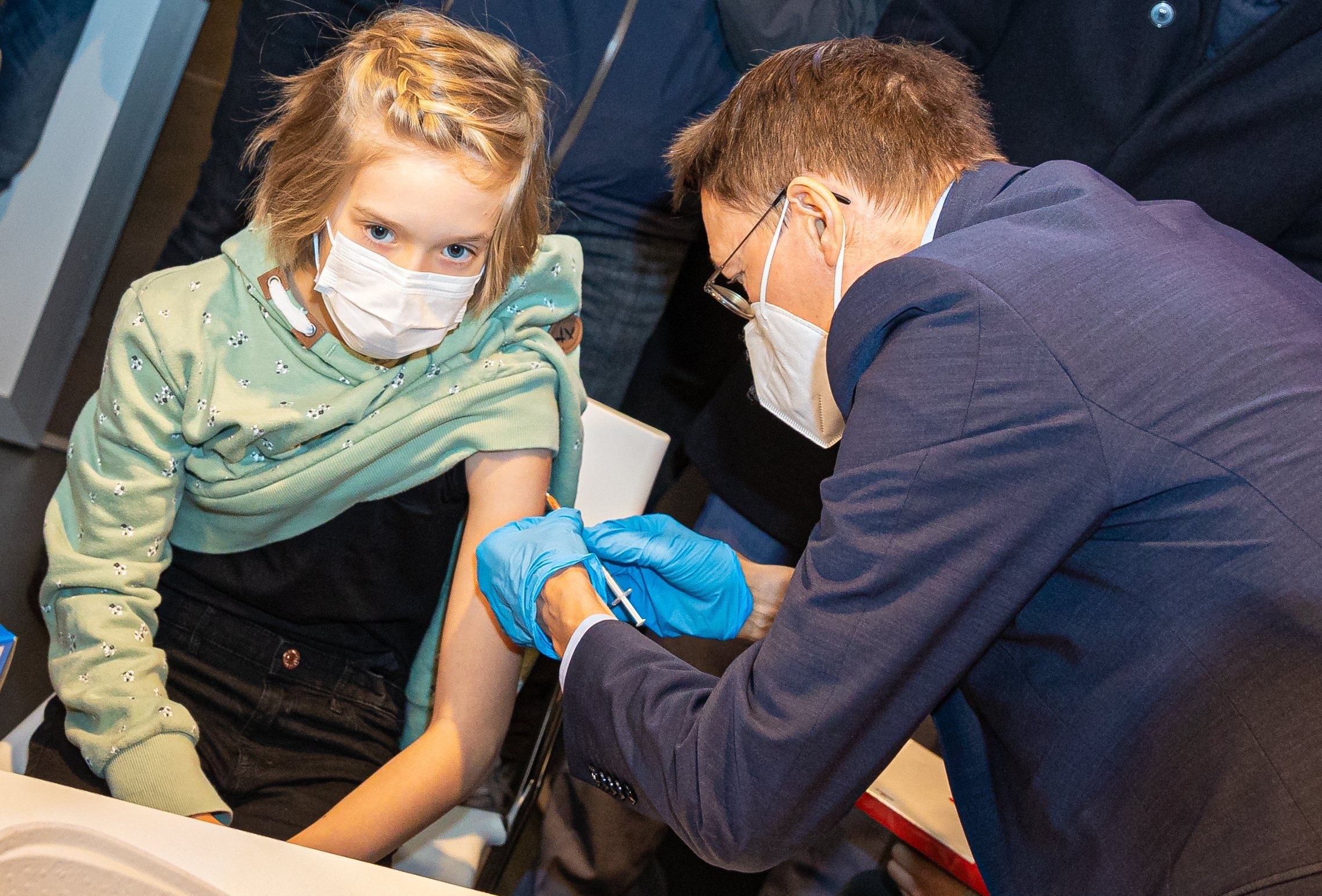 وزير الصحة الألماني كارل لوترباخ (يمين) بتلقيح طفلة خلال زيارة لأحد مراكز التطعيم في 17 ديسمبر 2021 (د ب ا)