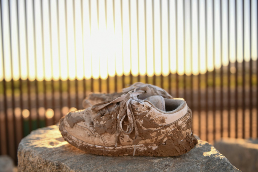 زوج من الأحذية المتقشرة بالطين يقع بالقرب من فجوة على طول الجدار الحدودي بين الولايات المتحدة والمكسيك في يوما ، أريزونا في 31 مايو 2022 (ا ف ب)